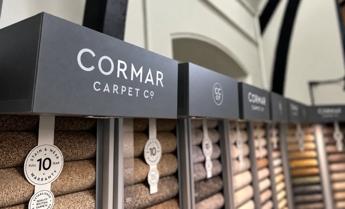 Cormar Carpet Co. display signs above carpet sample rolls in the showroom